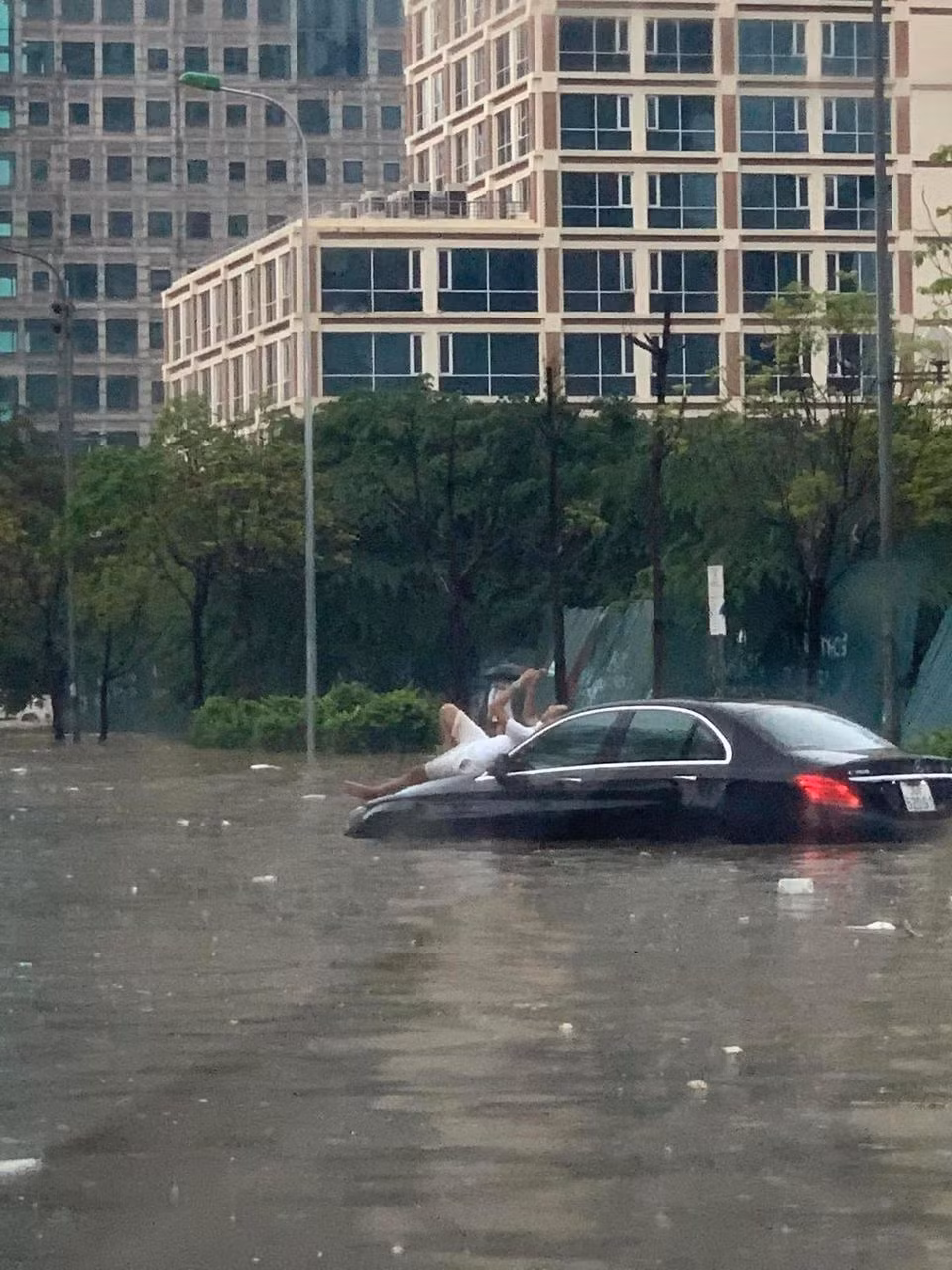 Hình ảnh một tài xế vô tư nằm trên đầu xe ô tô chờ nước rút đang được cư dân mạng chia sẻ nhiều trên MXH. Ảnh: Dân Trí