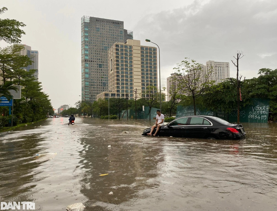 Có lẽ vì nước ngập quá sâu, cũng có thể do chết máy mà người tài xế này phải tìm cách thoát khỏi tình cảnh éo le là nằm trên đầu xe ô tô. Ảnh: Dân Trí