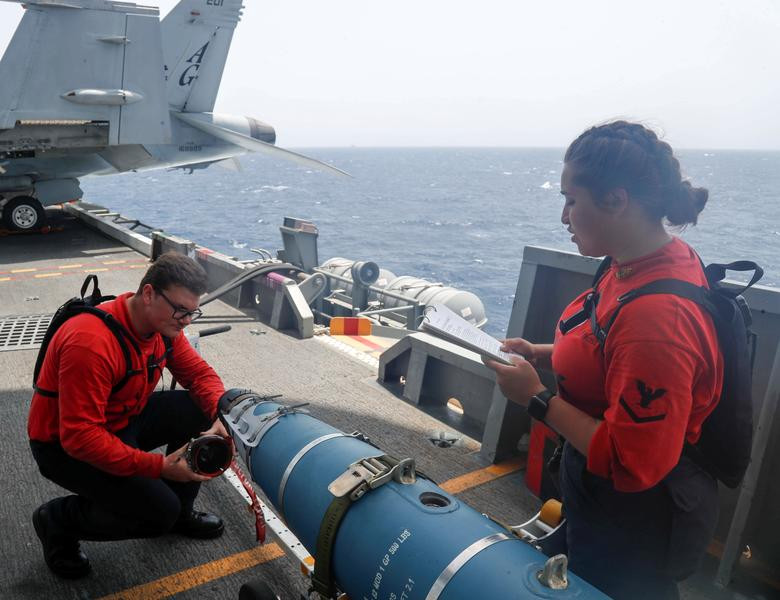 Thuỷ thủ trên tàu sân bay USS Abraham Lincoln kiểm tra và lắp đầu đạn cho một quả bom ngay trên boong tàu. Nguồn ảnh: Reuters.