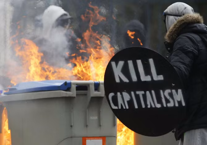 Người biểu tình đeo mặt nạ tập trung gần những thùng rác đang bốc cháy trong cuộc đụng độ với cảnh sát Pháp.