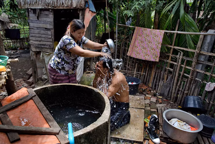 Anh được chị gái tắm cho sau khi về quê ở tỉnh Mon, Myanmar. (ảnh: AP)