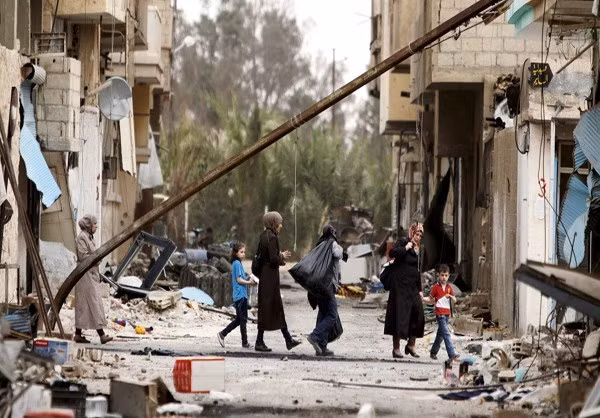 Người dân đi qua một con đường ở thành phố cổ Palmyra còn ngổn ngang những đống đổ nát.