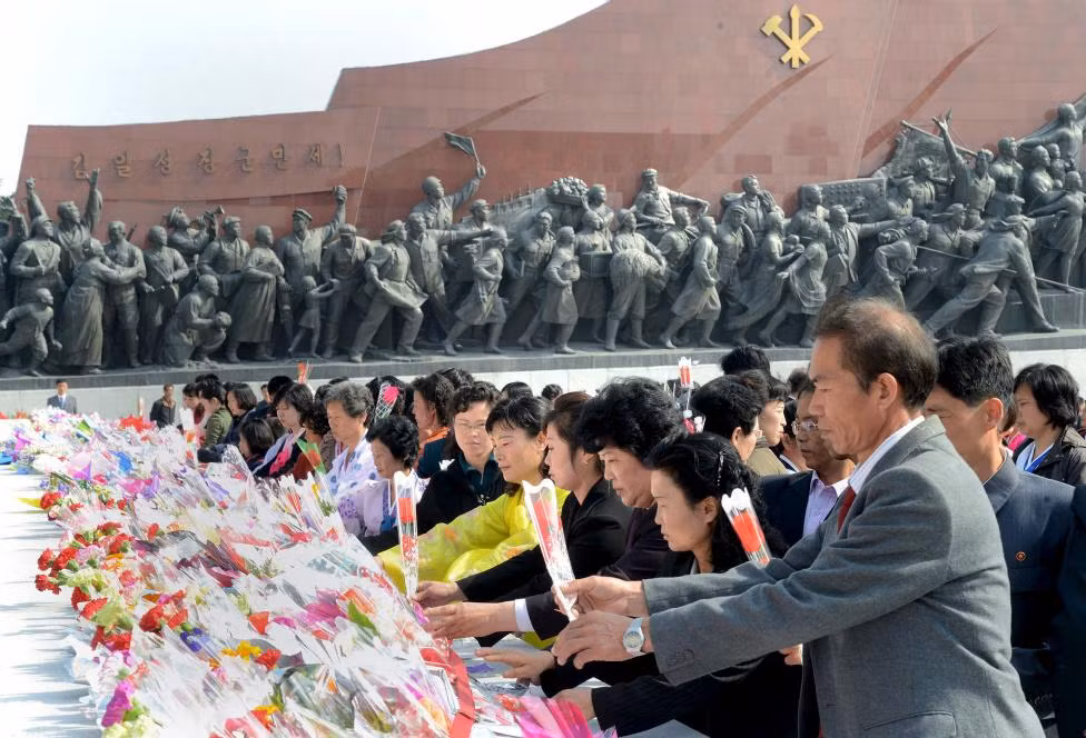 Người dân đặt hoa tưởng niệm ở khu vực tượng đài cố lãnh đạo Kim Il-sung và con trai của ông, Kim Jong-il.