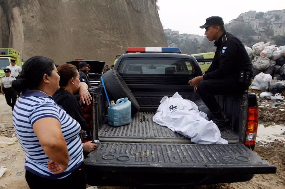 Nguyên nhân vụ sạt lở ở bãi rác Guatemala được cho là do mưa to. Được biết, bãi rác khổng lồ này tiếp nhận khoảng 500 xe tải chở rác mỗi ngày. Ảnh: Cảnh sát ngồi cạnh thi thể một người nhặt rác phía sau xe hôm 27/4.