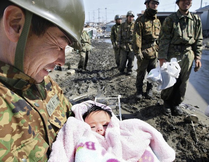 Một người lính tự vệ Nhật Bản mỉm cười khi bế một em bé sống sót sau trận sóng thần tàn khốc năm 2011.
