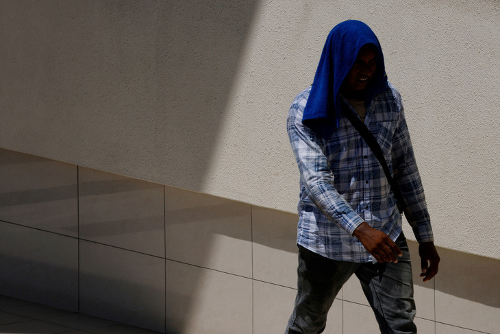 Người công nhân nhập cư dùng khăn che đầu để tránh cái nóng oi bức ở Singapore hôm 15/5. Ảnh: REUTERS.