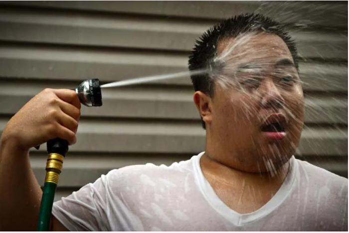 Người đàn ông ở Thái Lan đang xịt nước vào mặt để giảm cái nóng mùa hè. Ảnh: INVESTVINE.