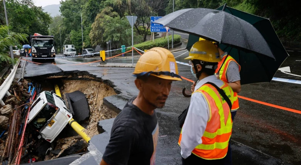Một chiếc xe hơi bị sụp xuống hố sâu giữa đường. Ảnh: Reuters, IT.