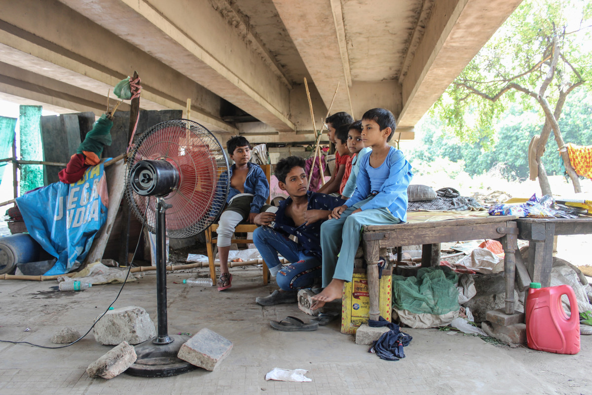 Những đứa trẻ vô gia cư ngồi hóng mát bên chiếc quạt điện duy nhất của 15 gia đình sống dưới gầm cầu ở khu vực Moolchand Basti, New Delhi. Ảnh: Jazeera.