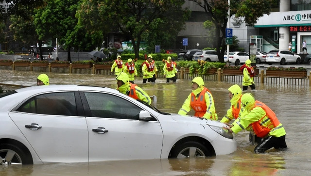 Lực lượng cứu hộ đẩy một chiếc ô tô bị mắc kẹt trên đường phố ngập nước. Ảnh: VCG.