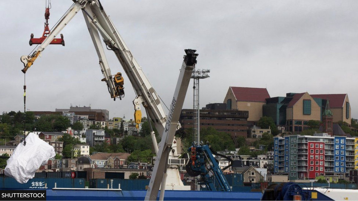 Ảnh chụp và video cho thấy các miếng kim loại lớn được phủ bằng vải bạt đã được cần cẩu nhấc lên xe tải.