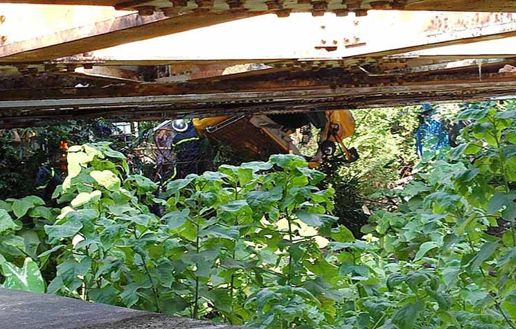 Một phần thân xe ô tô bị tàu hỏa đâm văng ra khỏi đường ray, rơi xuống kênh nước.