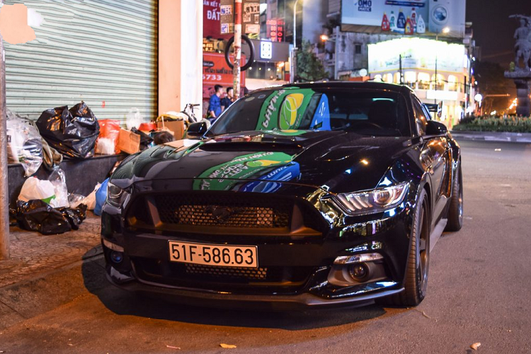 Tiếp đến chính là chiếc Ford Mustang Convertible màu trắng được nâng cấp ngoại thất bằng những trang bị cánh gió cỡ lớn, bộ lip hông, lip cản trước, mâm độ và cả phuộc nâng hạ gầm. Chiếc xe được trang bị bộ mâm đa chấu cỡ lớn phối giữa hai tông màu đen – vàng khá nổi bật. Nắp capo nguyên bản cũng được thay thế bằng nắp capo mới làm bằng chất liệu carbon.