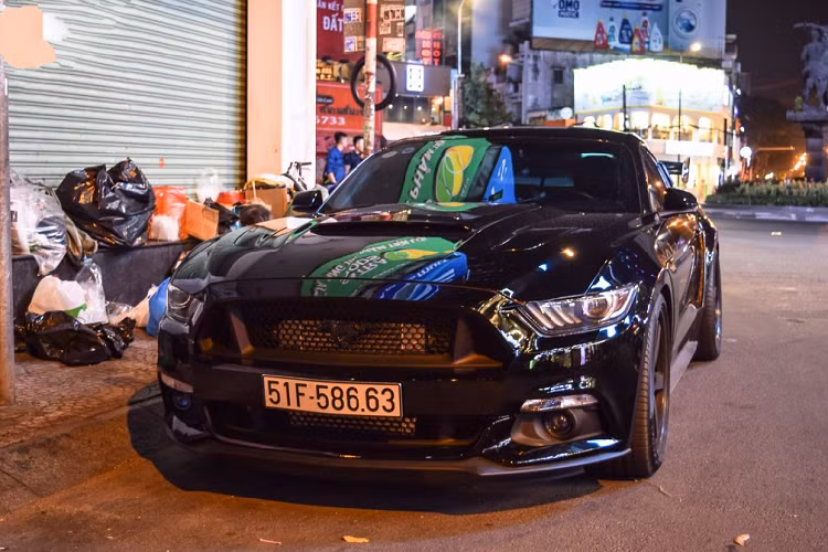 Tiếp đến chính là chiếc Ford Mustang Convertible màu trắng được nâng cấp ngoại thất bằng những trang bị cánh gió cỡ lớn, bộ lip hông, lip cản trước, mâm độ và cả phuộc nâng hạ gầm. Chiếc xe được trang bị bộ mâm đa chấu cỡ lớn phối giữa hai tông màu đen – vàng khá nổi bật. Nắp capo nguyên bản cũng được thay thế bằng nắp capo mới làm bằng chất liệu carbon.