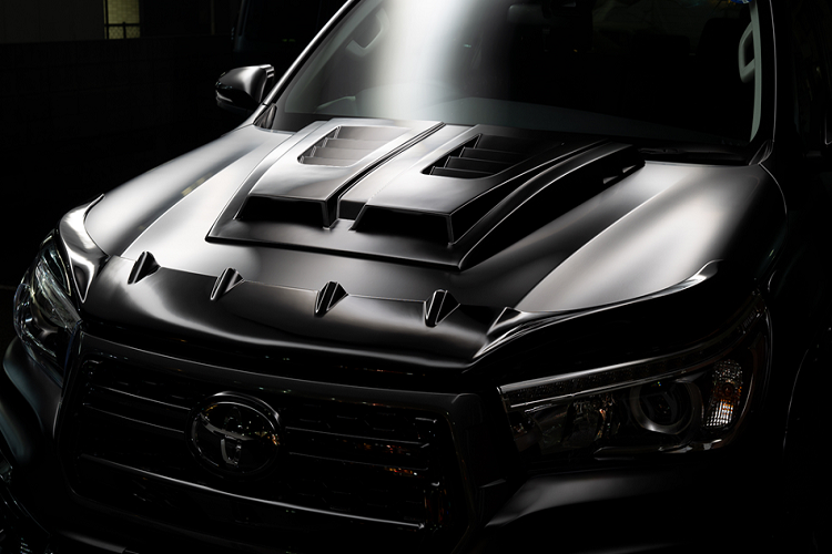 Trên nắp capô, gói độ cung cấp thêm cánh lướt gió ở mũi xe và bộ ốp hốc lấy gió trông rất cơ bắp. Hai chi tiết này vừa tăng tính thẩm mỹ, vừa giúp cải thiện khả năng vận hành cho mẫu pick-up của Toyota.