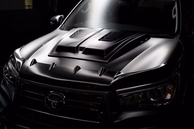 Trên nắp capô, gói độ cung cấp thêm cánh lướt gió ở mũi xe và bộ ốp hốc lấy gió trông rất cơ bắp. Hai chi tiết này vừa tăng tính thẩm mỹ, vừa giúp cải thiện khả năng vận hành cho mẫu pick-up của Toyota.