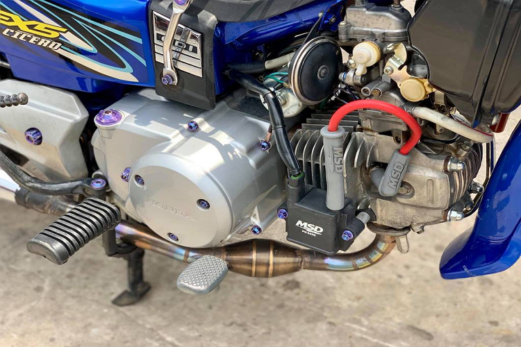 Bình dầu phanh AEM được giấu gọn gàng dưới cổ xe ở bên phải, trong khi bên trái là sự xuất hiện của đèn LED L4 và trợ lực Matris. Những món phụ tùng quen thuộc của dân chơi Dream "kiểng" như baga sau cùng baga sườn 10 li, giỏ xe phía trước... cũng xuất hiện đầy đủ trên bản độ này.