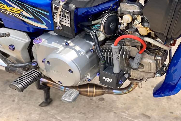 Bình dầu phanh AEM được giấu gọn gàng dưới cổ xe ở bên phải, trong khi bên trái là sự xuất hiện của đèn LED L4 và trợ lực Matris. Những món phụ tùng quen thuộc của dân chơi Dream "kiểng" như baga sau cùng baga sườn 10 li, giỏ xe phía trước... cũng xuất hiện đầy đủ trên bản độ này.