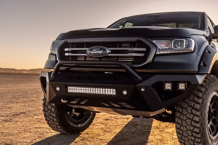 Ở phần đầu xe, bộ cản dưới đã được lược bỏ để thay bằng tấm chắn kim loại màu đen cùng bộ đèn LED siêu sáng giúp gia tăng cái nhìn mạnh mẽ. Nắp ca-pô nguyên bản cũng được các kỹ sư của Hennessey thay thế bằng loại có nhiều gân dập nổi hơn. Bên cạnh đó, bộ mặt ca-lăng mới với 2 nan kép sơn màu nhôm khói và logo Ford to bản ở giữa cũng mang tới diện mại cơ bắp hơn đáng kể. Cận cảnh phần đầu xe với bộ cản dưới đóng logo VelociRaptor