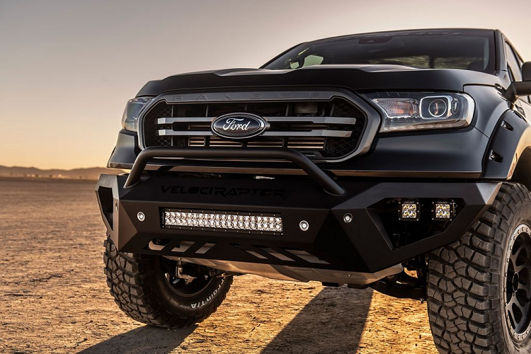 Ở phần đầu xe, bộ cản dưới đã được lược bỏ để thay bằng tấm chắn kim loại màu đen cùng bộ đèn LED siêu sáng giúp gia tăng cái nhìn mạnh mẽ. Nắp ca-pô nguyên bản cũng được các kỹ sư của Hennessey thay thế bằng loại có nhiều gân dập nổi hơn. Bên cạnh đó, bộ mặt ca-lăng mới với 2 nan kép sơn màu nhôm khói và logo Ford to bản ở giữa cũng mang tới diện mại cơ bắp hơn đáng kể. Cận cảnh phần đầu xe với bộ cản dưới đóng logo VelociRaptor