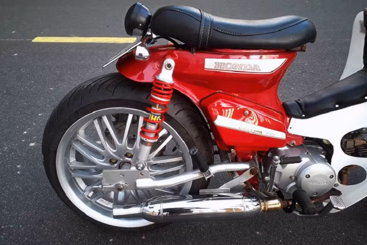 Trong khi đó, bánh sau có bộ gắp hoàn toàn mới, được gia công từ thép ống. Các tai bắt phuộc trên khung cũng đã được nới rộng. Ngay cả những chiếc mâm cũng đã phải được chủ xe tiện moay-ơ riêng để lắp được bánh lớn. Cặp moay-ơ này đồng thời là điểm bắt những đĩa phanh, nâng cấp hệ thống phanh đùm lên thành phanh đĩa an toàn hơn.