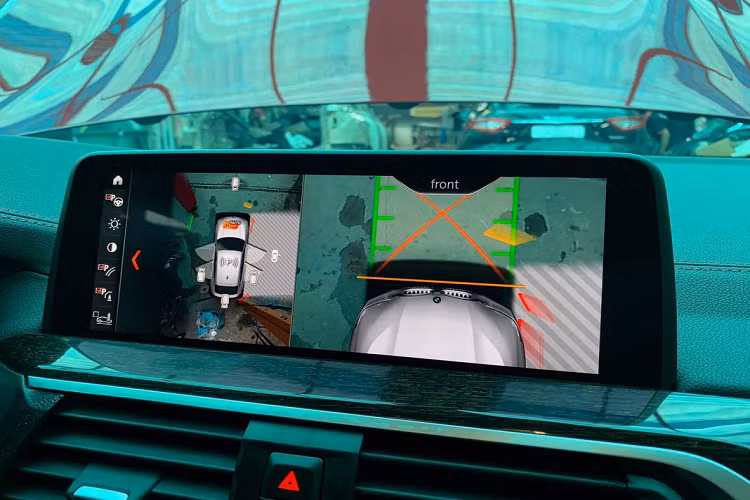 Cần số có logo M. Phía trước vô-lăng còn có màn hình hắt kính HUD. Màn hình chính giữa xe hỗ trợ Apple CarPlay, hiển thị camera 360 độ. Trên X4 chính hãng, xe chỉ có cảm biến xung quanh và camera lùi.