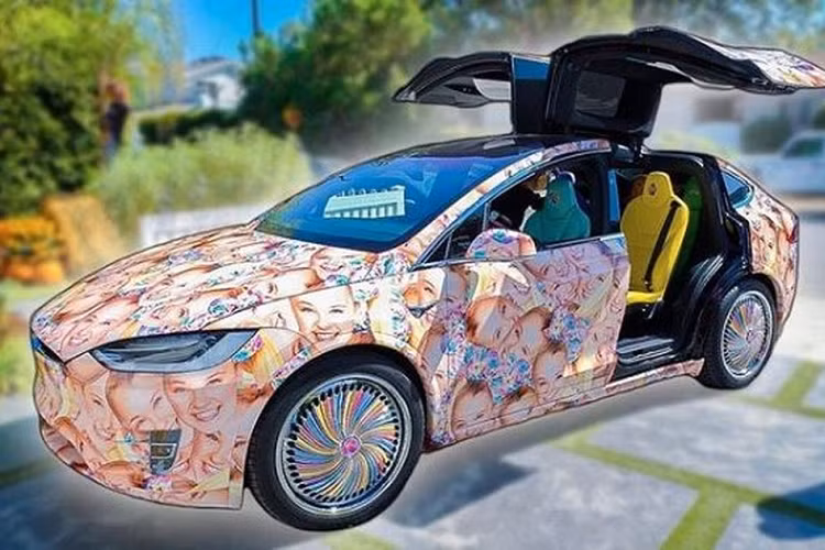 JoJo Siwa với chiếc Tesla Model X tràn ngập hình ảnh khuôn mặt của chính mình. Những người bạn đã gửi tặng JoJo một chiếc Tesla Model X với thiết kế tràn ngập hình ảnh khuôn mặt của cô ấy, bánh xe sơn màu cầu vồng và ghế ngồi với nhiều màu sắc khác nhau. Trái ngược hẳn với thiết kế nguyên bản nhẹ nhàng và lịch sự, chiếc Model X này đã trở nên sặc sỡ tới lố bịch!