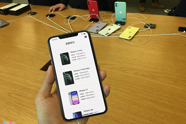 Giá các loại iPhone 11 tại Thượng Hải, Trung Quốc. Giá một chiếc iPhone Pro Max 64 GB tại đây khoảng 31,5 triệu đồng, thấp hơn mức dự kiến tại Việt Nam (34 triệu). Ở phía sau, hàng loạt sản phẩm mẫu bị vứt lăn lóc, không được gắn lên dock sạc sau khi trải nghiệm. 