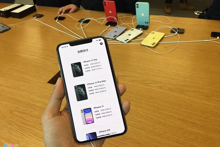 Giá các loại iPhone 11 tại Thượng Hải, Trung Quốc. Giá một chiếc iPhone Pro Max 64 GB tại đây khoảng 31,5 triệu đồng, thấp hơn mức dự kiến tại Việt Nam (34 triệu). Ở phía sau, hàng loạt sản phẩm mẫu bị vứt lăn lóc, không được gắn lên dock sạc sau khi trải nghiệm. 