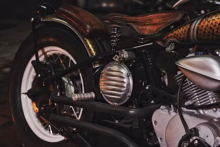 Dù không có dè trước, nhưng bản độ vẫn được 3D lắp cho chiếc vè sau cổ điển với yên phụ nằm ở phí trên. Có kinh nghiệm trong việc phay và gò nhôm, xưởng độ đã tạo ra một loạt các chi tiết "thửa riêng" từ loại vật liệu này như những tấm chắn hộp điện hình tròn hai bên thân xe, gác chân, nắp bình xăng... Để khiến Roadhopper có vẻ ngoài cổ điển thuần chất, 3D đã lựa chọn cặp bánh với lốp thành cao kiểu Firestone cho xe, bọc xung quanh niềng sơn trắng và có moay-ơ phanh đùm phía trước to bản. 