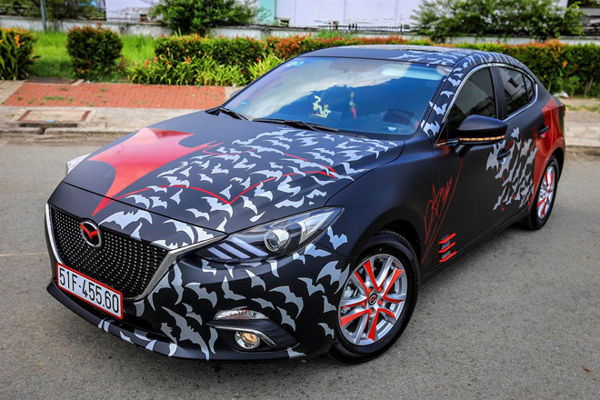 Mazda3 2017 dán tem Batman, độ đồ chơi tại Sài Gòn. Chiếc Mazda3 2017 thuộc sở hữu của một chủ xe trẻ tuổi tại TP.HCM. Sau khi chọn mua mẫu sedan này, chủ xe đã dán decal đen mờ toàn bộ cho thân xe, khiến chiếc xe hút mắt hơn. Chữ ký của chủ xe cũng được làm từ decal và dán lên sườn xe.