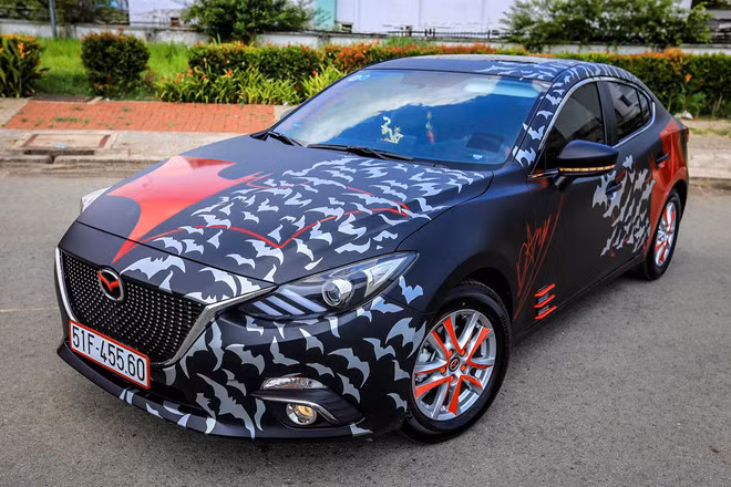 Mazda3 2017 dán tem Batman, độ đồ chơi tại Sài Gòn. Chiếc Mazda3 2017 thuộc sở hữu của một chủ xe trẻ tuổi tại TP.HCM. Sau khi chọn mua mẫu sedan này, chủ xe đã dán decal đen mờ toàn bộ cho thân xe, khiến chiếc xe hút mắt hơn. Chữ ký của chủ xe cũng được làm từ decal và dán lên sườn xe.