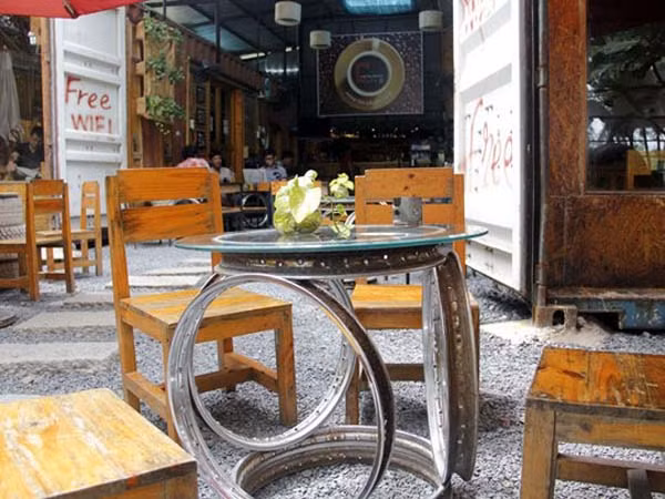 Cùng với bàn ghế gỗ, Café Contaier còn tận dụng những phụ tùng bỏ đi như vỏ xe, mâm, sên cam, vòng bi, bạc đạn... làm thành bàn uống nước và những đồ trang trí nội thất của quán nhằm gây ấn tượng với khách. Nguồn ảnh: Internet.