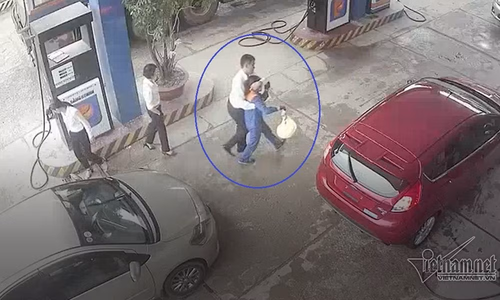 Khách hàng dìu nhân viên bơm xăng đi vào bên trong cửa hàng.