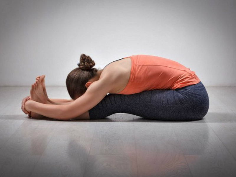 Bạn chỉ cần ngồi trên sàn, hai chân duỗi thẳng phía trước, hít sâu, duỗi toàn thân về phía trước, lõm phần lưng xuống, hai bàn tay nắm lấy ngón chân cái, trán đặt lên đầu gối. Ảnh: theducthammydangngoc.