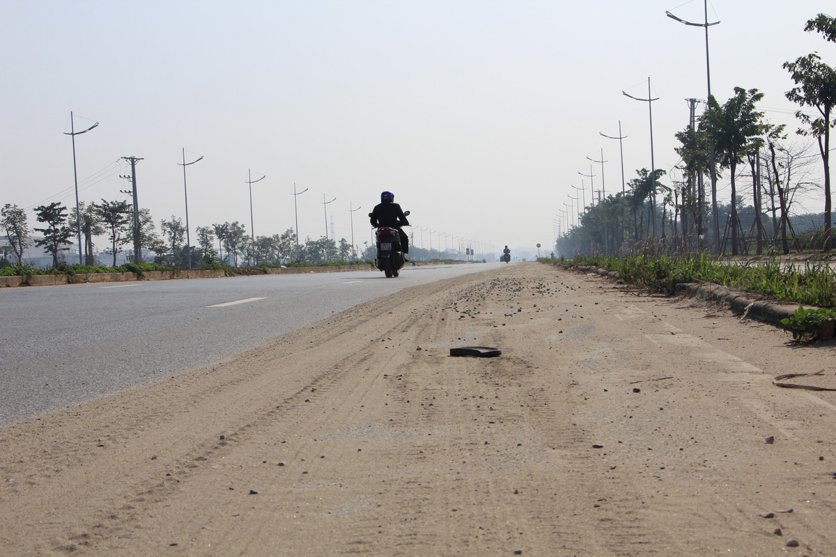 Lớp đất cát phủ dày một nửa làn đường không được quét dọn.