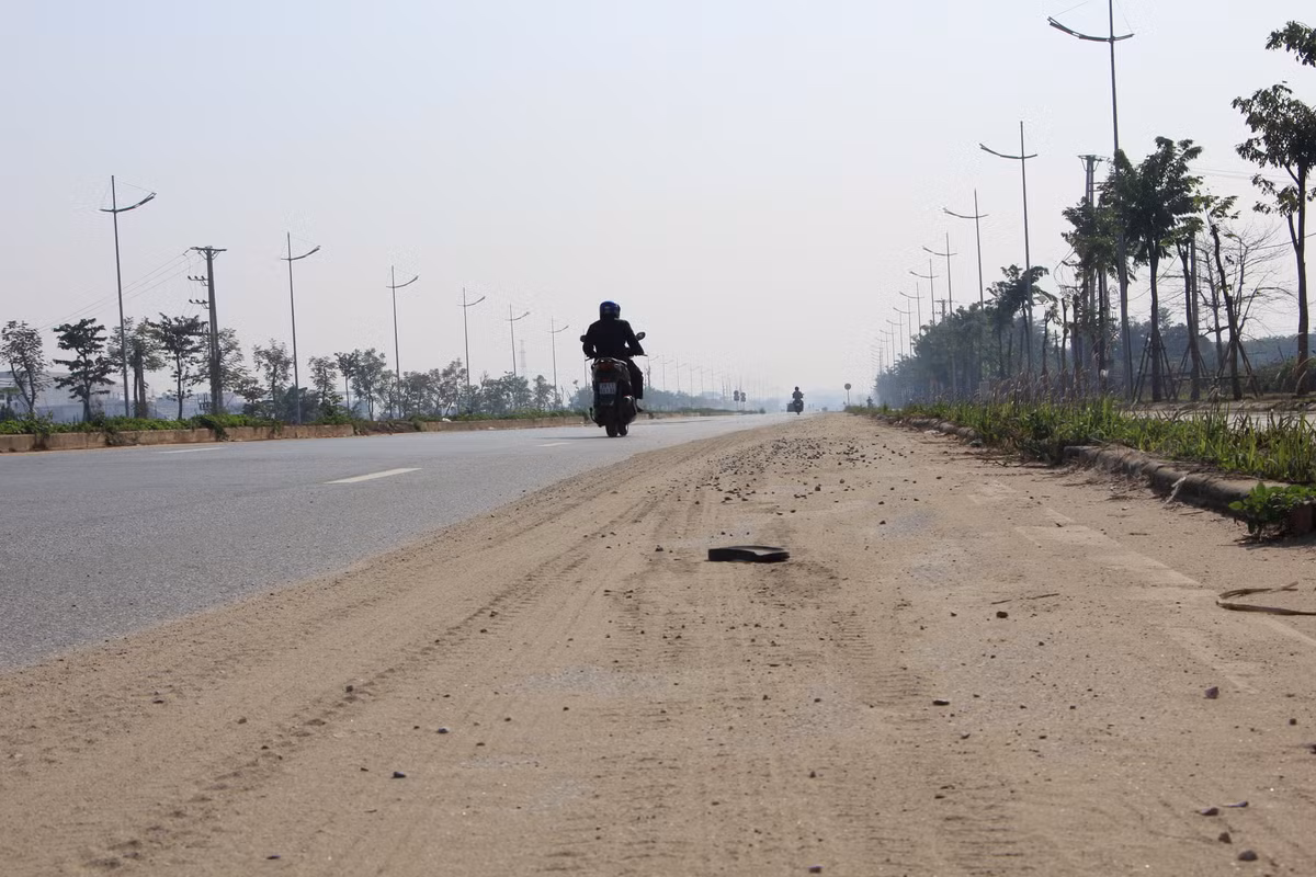 Lớp đất cát phủ dày một nửa làn đường không được quét dọn.