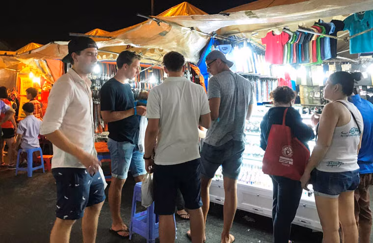 Du khách nước ngoài mua sắm tại chợ đêm Bến Thành.