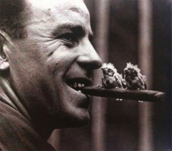 Một người đàn ông giữ điếu xì gà trên miệng với 2 chú chim hoàng yến đậu trên đó năm 1918./.