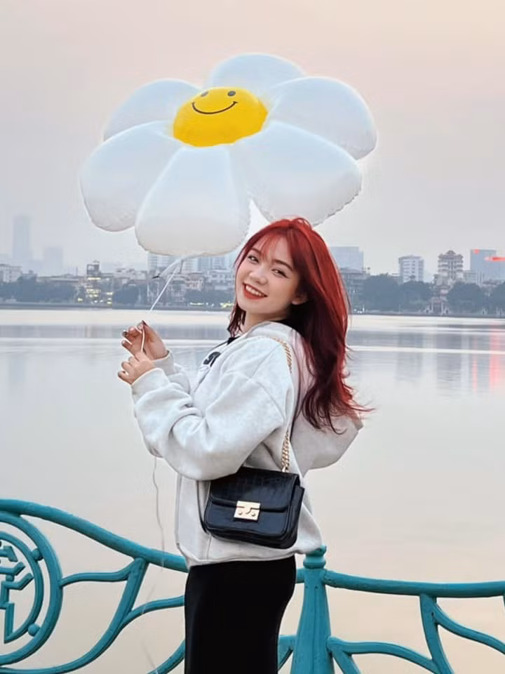 Hình ảnh giới trẻ tạo dáng bên bóng bay hoa cúc tại hồ Tây. Ảnh: Hà Phương