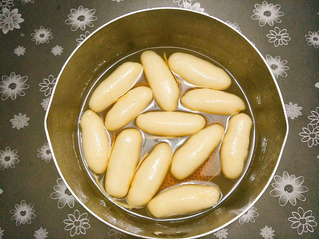 Cho mật mía hoặc đường thốt nốt vào nồi, bạn có thể tự điều chỉnh độ ngọt theo sở thích. Nếu bạn dùng đường thốt nốt thì thêm một chút nước nấu cho đường tan hết. Tiếp theo bạn cho gừng thái sợi vào nồi sau đó vớt bánh ngào sang nồi nước đường, nấu thêm 1-2 phút cho bánh ngấm nước mật là có thể tắt bếp.