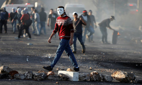 Một người Palestine bịt mặt tham gia biểu tình phản đối tuyên bố Jerusalem của ông Trump tại khu vực gần thành phố Ramallah ở khu Bờ Tây - Ảnh: REUTERS