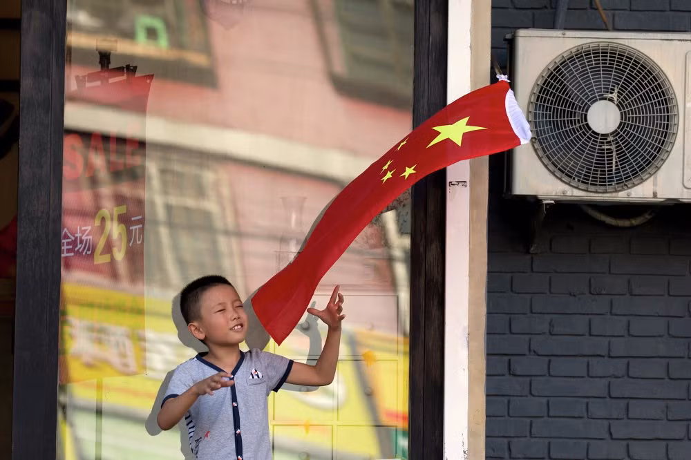 Một đứa trẻ đang đùa nghịch với lá quốc kỳ gần khu vực diễn tập.