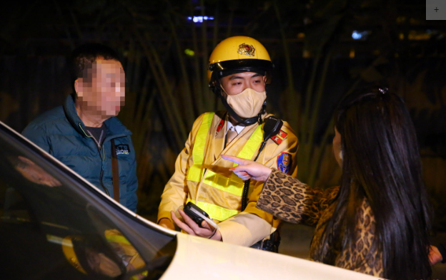  Chồng vi phạm nồng độ cồn, vợ điện thoại "cầu cứu" rồi lăng mạ CSGT: Tối 20/12/2022, Đội CSGT số 3 (Phòng CSGT Hà Nội) tổ chức cắm chốt kiểm tra, xử lý đối với người vi phạm nồng độ cồn tại khu vực đường Láng (quận Đống Đa, Hà Nội). Khoảng hơn 22h đêm, tổ công tác dừng kiểm tra đối với tài xế điều khiển xe ô tô Mercedes BKS: 30E-973.XX do tài xế Nguyễn Văn D. (SN 1961; trú tại quận Ba Đình, Hà Nội) điều khiển chở theo vợ lưu thông về hướng Cầu Giấy. (Ảnh: CAND)