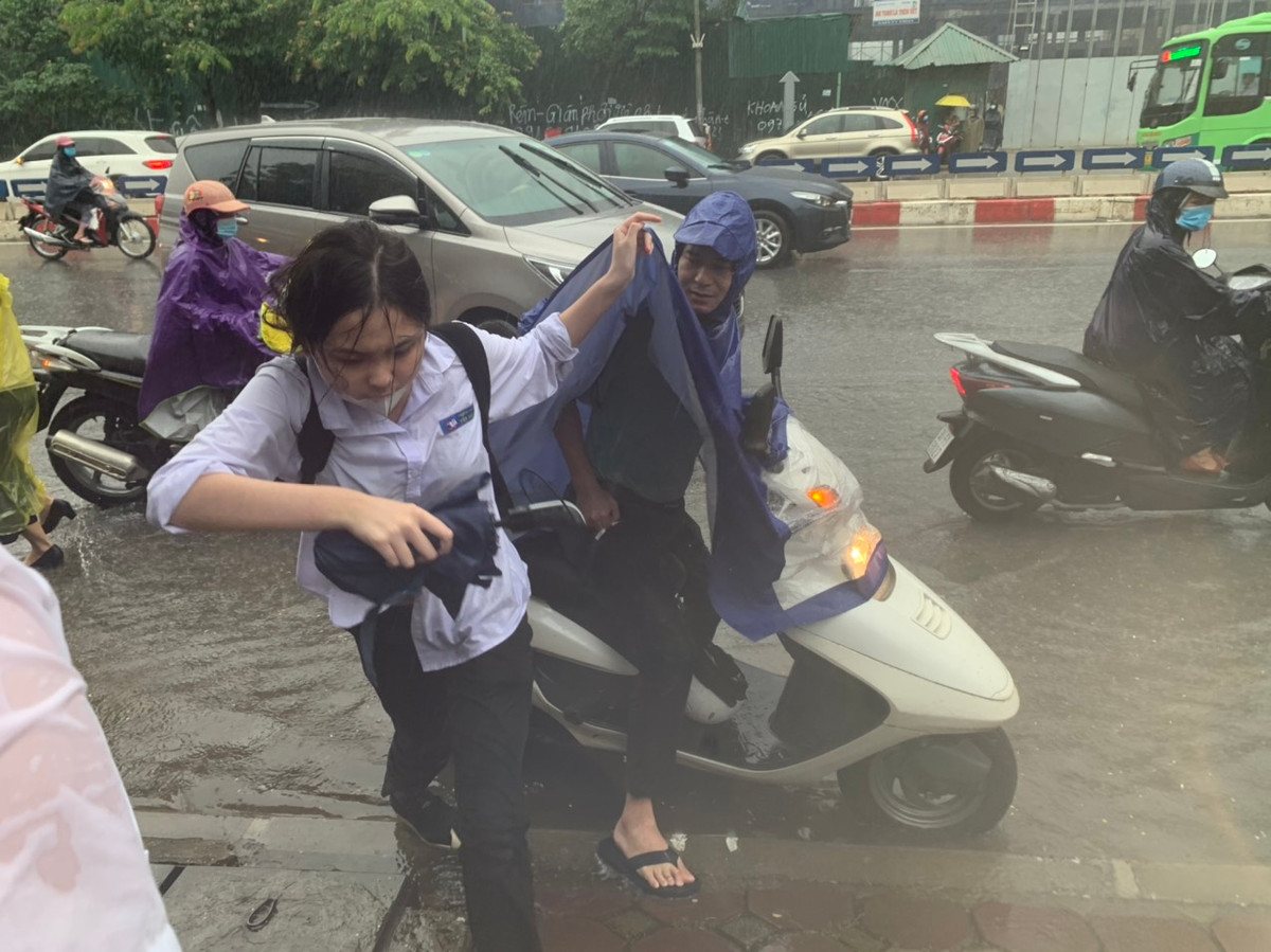 Phụ huynh đưa con đi thi tại điểm thi THPT chuyên Hà Nội - Amsterdam trong cơn mưa tầm tã.