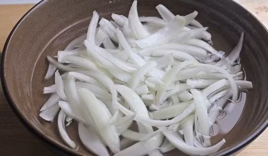 Hành tây xắt lát mỏng ngâm qua nước giấm đường cho bớt mùi hăng.