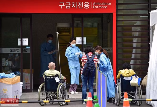 Nhân viên y tế phát khẩu trang cho du khách tới tham quan thủ đô Seol hôm 8/6.