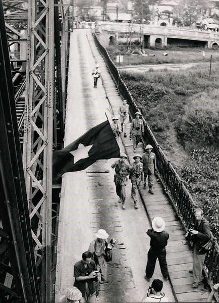 Kháng chiến chống Mỹ (còn được phía Mỹ gọi là chiến tranh Việt Nam) cũng nằm trong triển lãm. Đây được coi là cuộc chiến đầu tiên và duy nhất không bị kiểm duyệt, khi mà các phóng viên ảnh cả dày kinh nghiệm lẫn mới vào nghề có thể tới và tác nghiệp, thậm chí là giữa các trận đánh. Trong ảnh, quân Việt Minh vẫy cờ khi đi qua cầu Long Biên năm 1954. Ảnh: Không rõ người chụp.