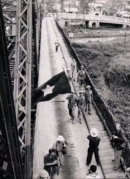 Kháng chiến chống Mỹ (còn được phía Mỹ gọi là chiến tranh Việt Nam) cũng nằm trong triển lãm. Đây được coi là cuộc chiến đầu tiên và duy nhất không bị kiểm duyệt, khi mà các phóng viên ảnh cả dày kinh nghiệm lẫn mới vào nghề có thể tới và tác nghiệp, thậm chí là giữa các trận đánh. Trong ảnh, quân Việt Minh vẫy cờ khi đi qua cầu Long Biên năm 1954. Ảnh: Không rõ người chụp.