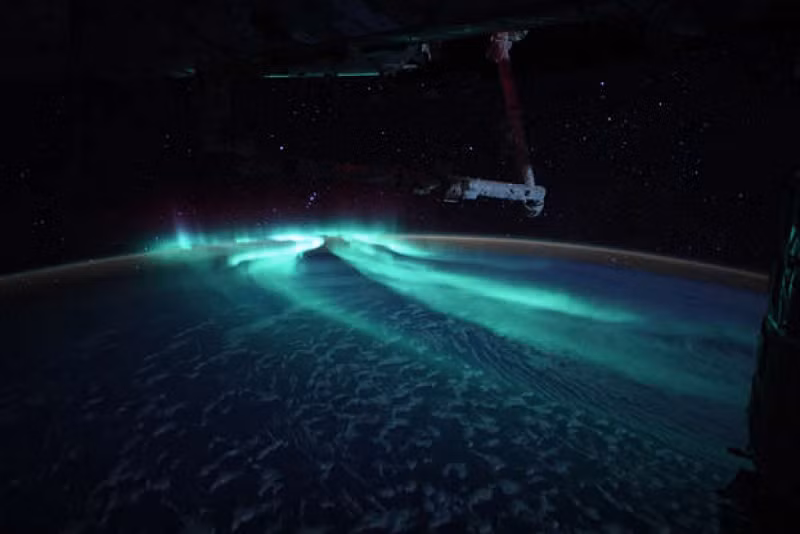 Mặt trăng chiếu sáng những đám mây bên dưới cực quang xanh đẹp mê hoặc.